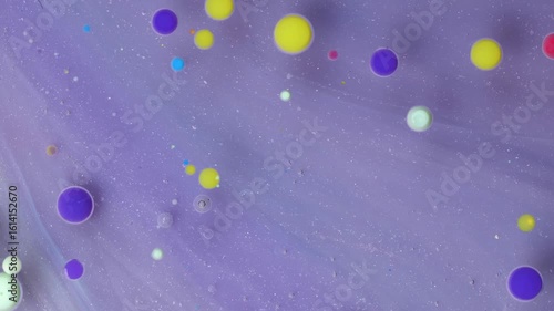 Acrylic paint drops mixing with oil create colorful patterns on a soft surface