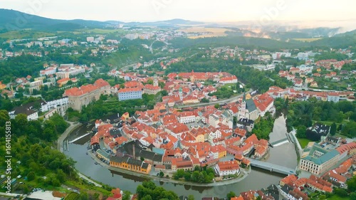 Experience a breathtaking morning view of Cesky Krumlov from above, showcasing its UNESCO heritage, winding river, and distinct architecture framed by lush greenery.