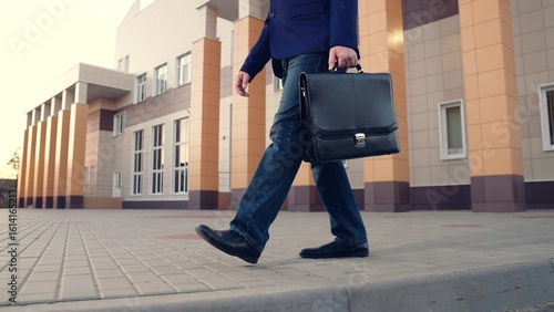 Businessman walking on sidewalk, people walking. Office pedestrian walking on city street to work. City life of people. Man with briefcase in business suit walking on street from work. Business, city