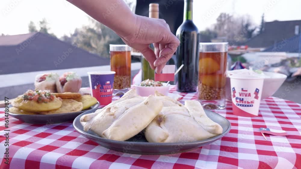 Chilean Independence Day video: Woman’s hand serving empanadas and placing flag on food at festive Chilean table