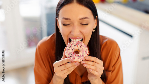 Hungry lady biting tasty doughnut, having cheat meal and eating junk food at home. Unhealthy nutrition and binge eating habit concept