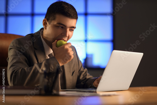 Young businessman eating ap...