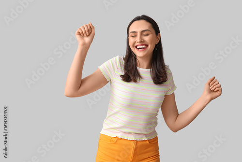 Smiling young woman on grey...