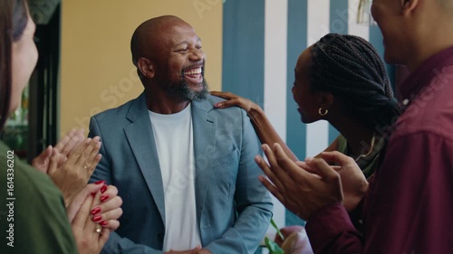 Group of diverse coworkers applauding black businessman in office space during daytime