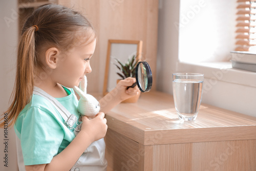 Cute little girl magnifying...
