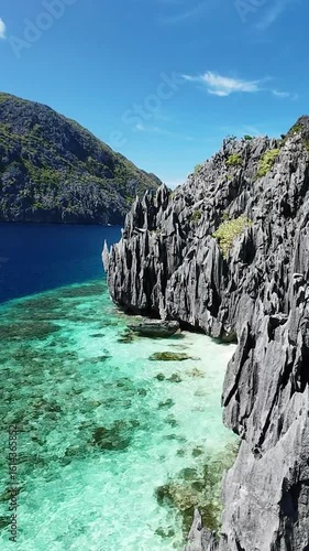 Sharp limestone formations and turquoise water in El Nido, Palawan seen from the sky. Drone view of dramatic cliffs and clear sea in El Nido, Philippines, vertical screen
