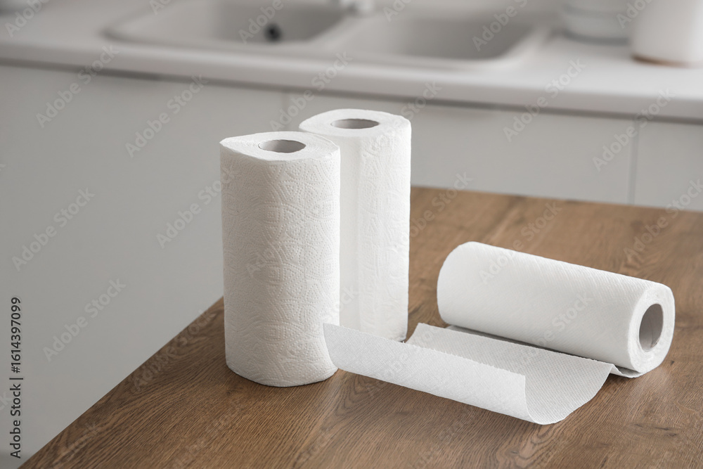 Fototapeta premium White paper towel rolls on wooden kitchen countertop, household cleaning and hygiene products