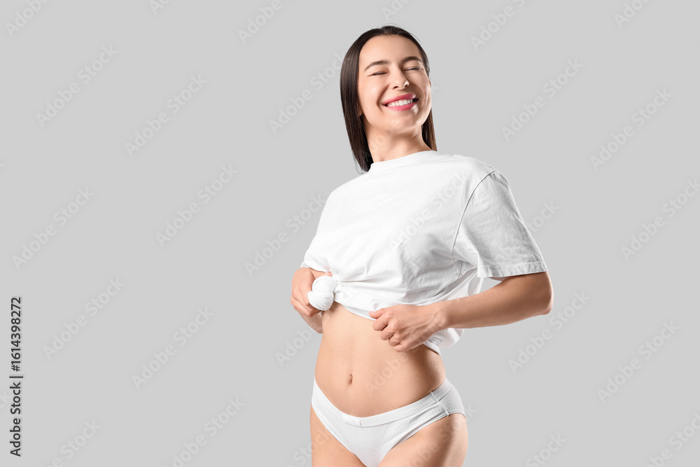 Fototapeta premium Happy young woman in stylish underpants and t-shirt posing on white background