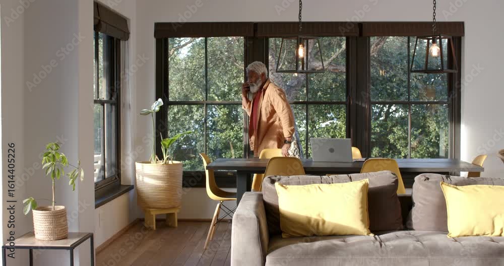 African American man answering smartphone call and pacing at home near window copy space African American man answering smartphone call and pacing at home near window copy space
