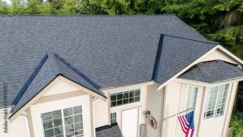 Brand new roof on a house in a residential neighborhood. The black shingles have been installed as a replacement on the older home for improvement. 