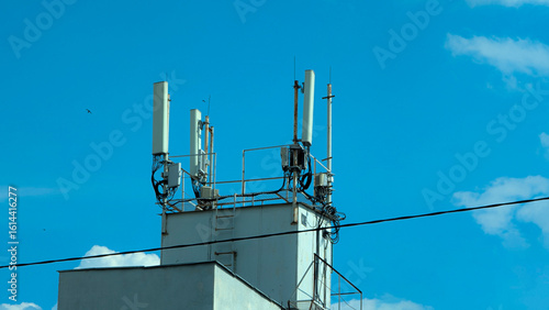 Mobile phone antennas on the roof of a building against the blue sky