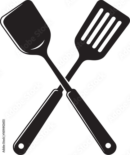 Two crossed kitchen spatulas one solid one slotted