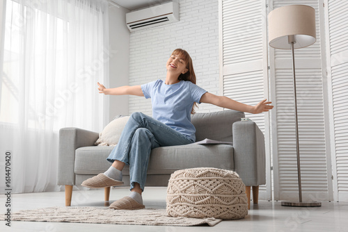 Young woman sitting on sofa...