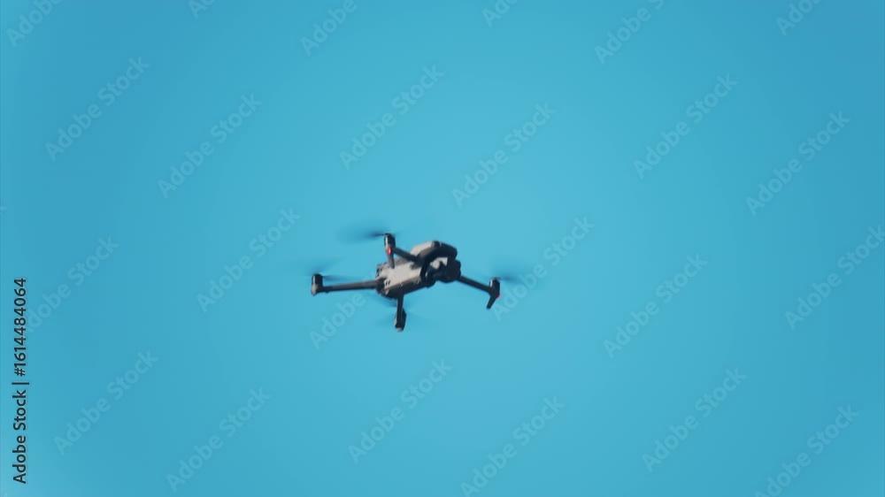 Low angle view of a drone hovering against a vivid blue sky Low angle view of a drone hovering against a vivid blue sky