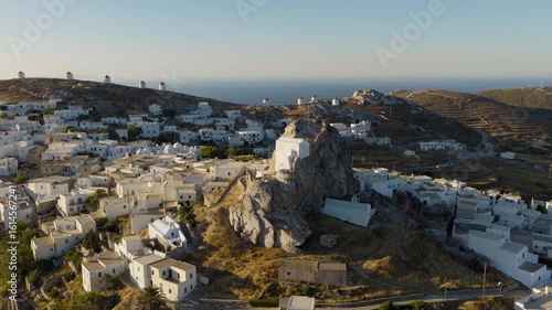 Aerial orbit around the medieval Castle of Amorgos in Chora during sunrise. The iconic Cycladic windmills create a timeless island backdrop