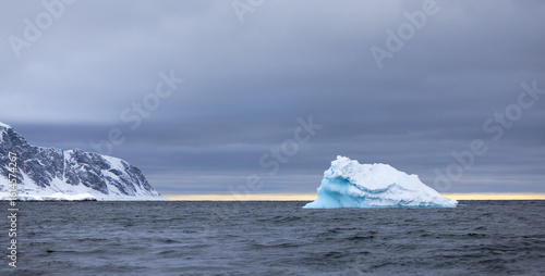 Blue iceberg from a glacier before a storm drifting in the ocean of Svalbard, Norway