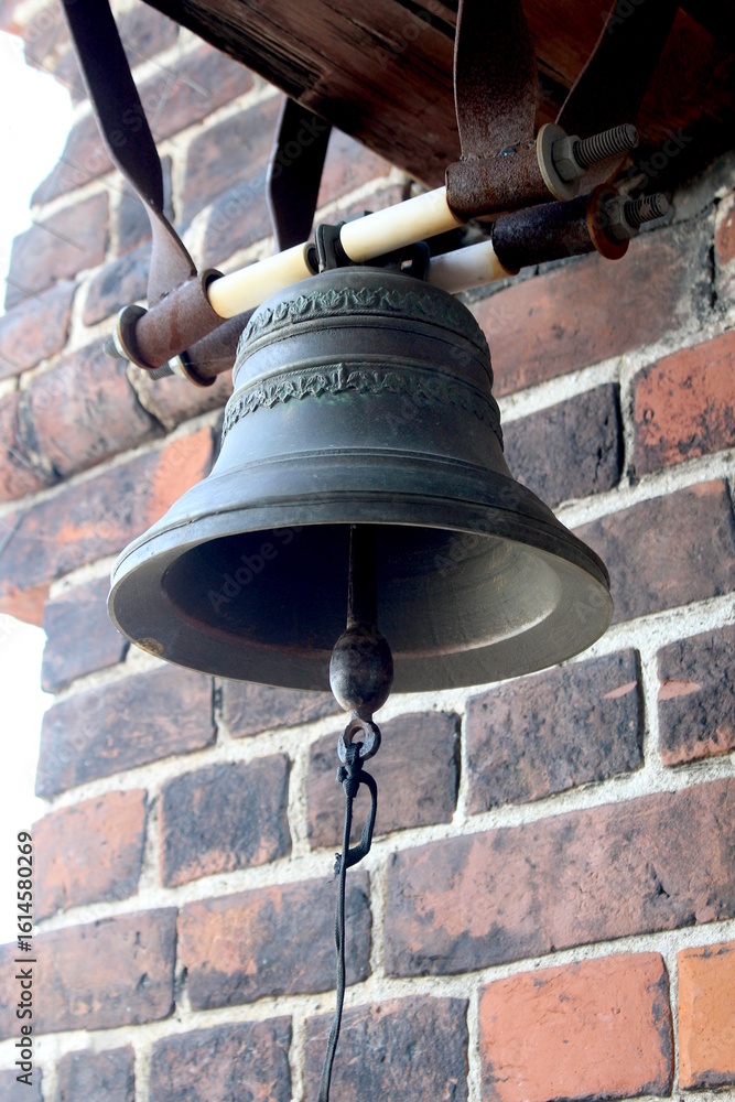 Fototapeta premium A small bell with a clapper hangs by the wall.