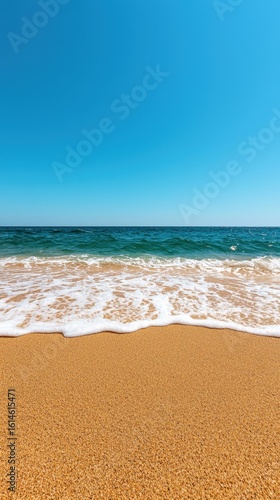 Tranquil Beach Scene with Golden Sand and Clear Blue Sky over Calm Ocean Waves