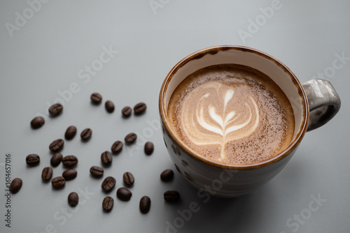 Rosetta Latte art in a ceramic cup  place on gray background  with copy space left, there are coffee beans around