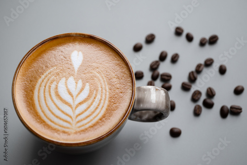 Tulip style Latte art in a ceramic cup  place on gray background  with copy space right, there are coffee beans around