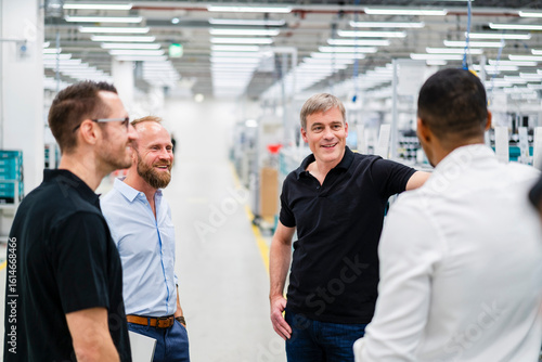 Smiling businessman and employees talking in a factory