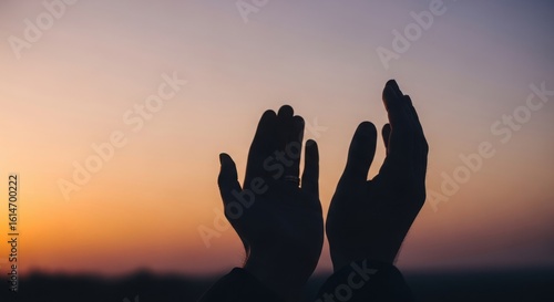 Two open hands reaching upwards towards a beautiful sunset sky silhouette