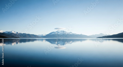 Fototapeta Naklejka Na Ścianę i Meble -  Serene landscape of a tranquil lake reflecting snowy mountains and a clear blue sky, capturing nature's perfect symmetry.