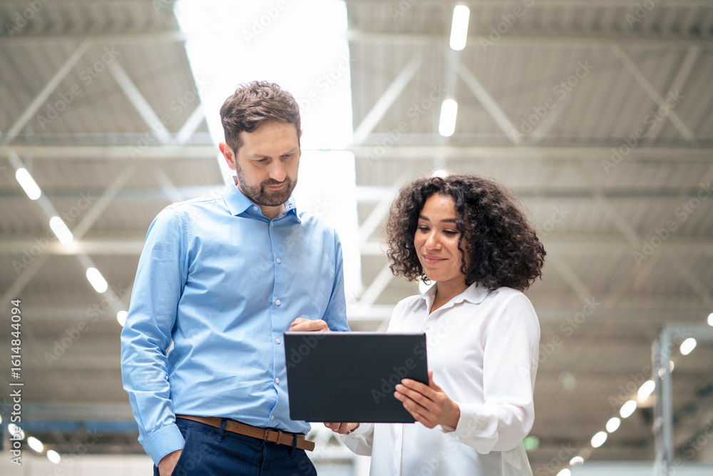 Smiling businesswoman discussing over tablet computer with colleague Smiling businesswoman discussing over tablet computer with colleague