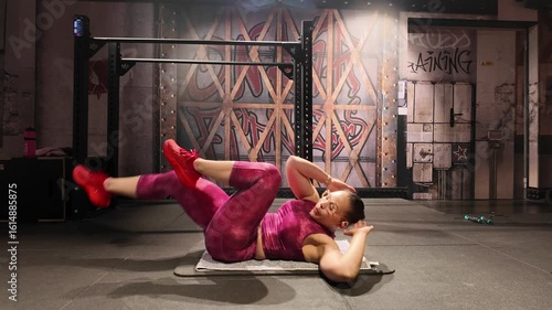 Fit woman performing bicycle crunches on a mat. She is strengthening her core and oblique muscles as part of a dedicated fitness routine in a gym