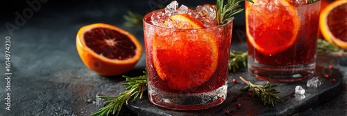 Blood orange spritz cocktail garnished with fresh rosemary sprig, served in a glass with ice, showcasing vibrant colors and refreshing appeal for summer gatherings and celebrations