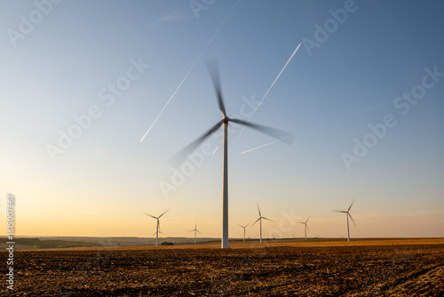 Renewable wind farm in rural region, turbines spinning under clear sky, producing clean energy without emissions, supporting environmental sustainability goals, future of energy captured in scenic