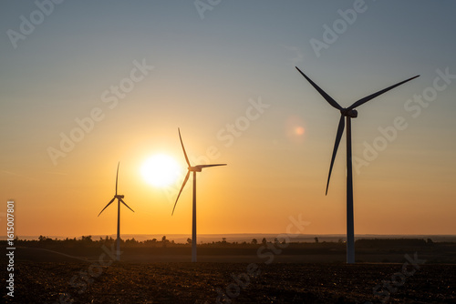 Modern wind generators installed across scenic landscape, harnessing wind energy to create sustainable electricity, eco-friendly solutions to climate issues, rural countryside during golden hour