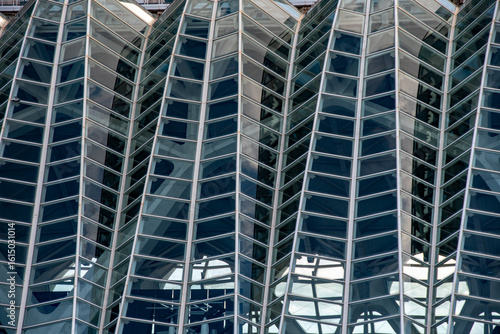 Modern architecture with angled glass windows. Facade of glass and metal. City centre and commerce.