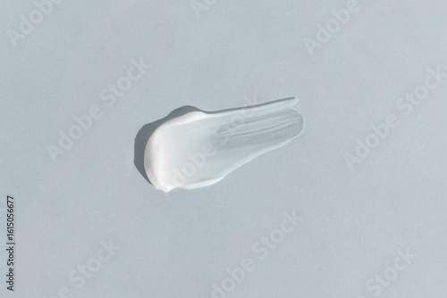 White cream texture on a light gray background. A smear of a cosmetic skin care product. Wellness and beauty concept.