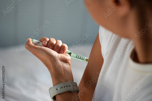 Close-up of woman injecting insulin in shoulder with pen
