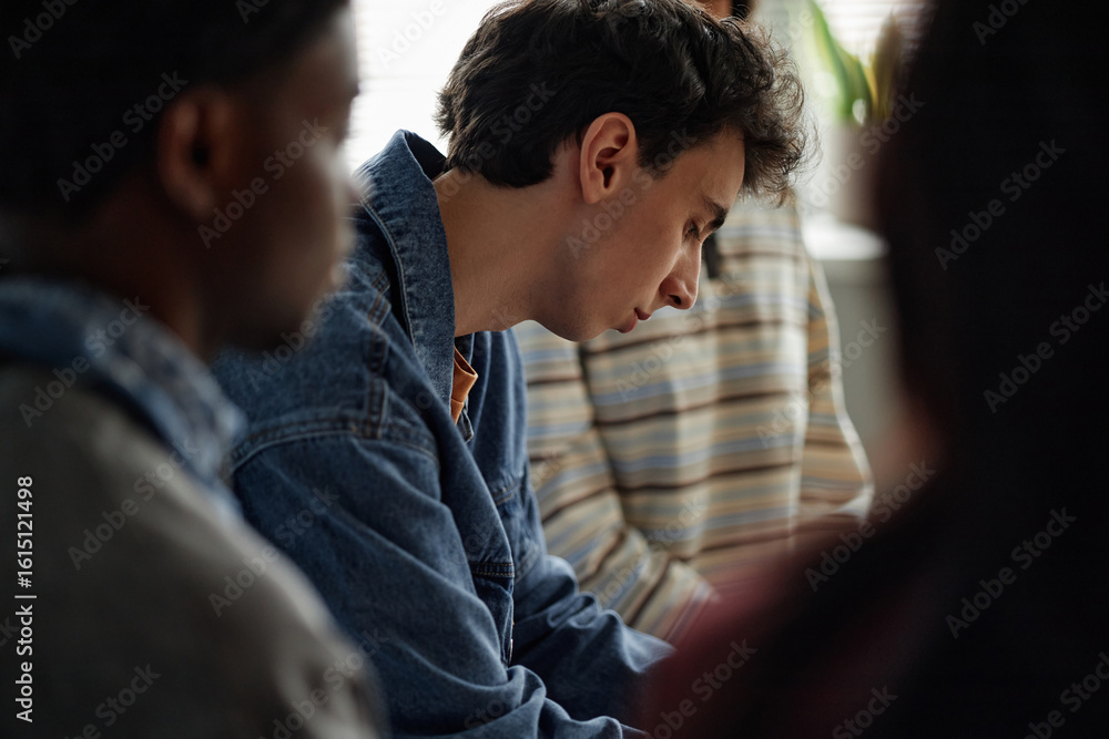 Obraz premium Multiethnic group of teenagers sitting together during counseling session, Caucasian teenage boy in focus listening attentively, other teenagers partially visible in background