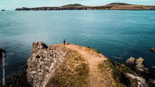 Εκτύπωση καμβά Man standing on the Pembrokeshire Coast looking over the sea to Ramsey Island
