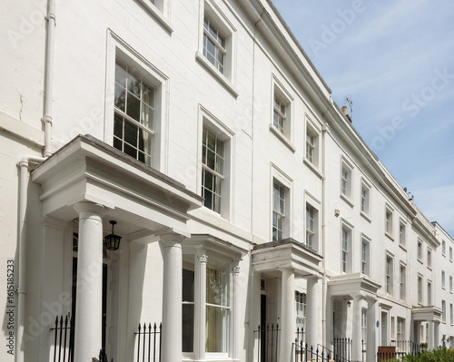 Row of elegant white Georgian terrace houses with white columns porch in Royal Leamington Spa, Warwickshire, United Kingdom. Townhouses with white luxury facade.