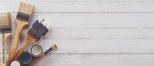 Several DIY paint supplies are placed on a white wooden background.