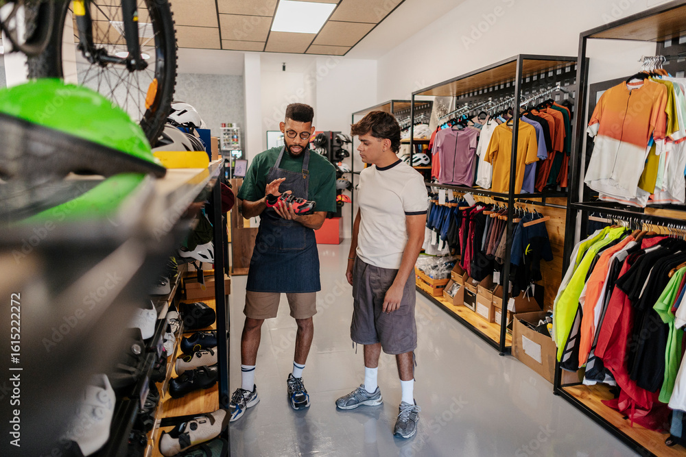 © PintoArt - Shop assistant showing cycling shoes to customer in bike shop