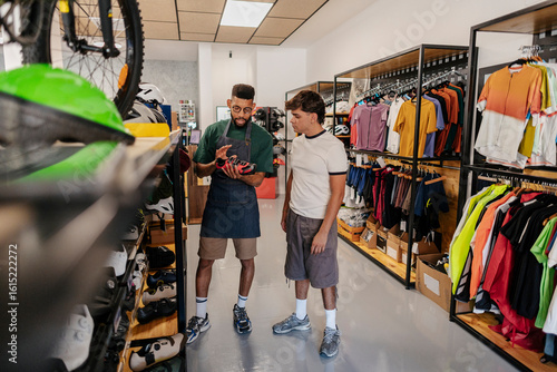 Shop assistant showing cycling shoes to customer in bike shop