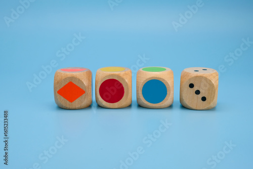 Schilderij op canvas Four wooden dice with vibrant colors and simple shapes colored circles, a diamond shape, and number dots placed in a row on a light blue background