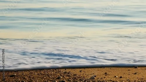 Tranquil beach scene with gentle waves lapping at sandy shore  