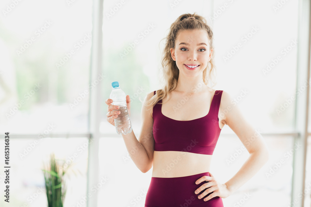 Young woman in activewear holding a water bottle indoors, promoting fitness, health, and lifestyle in a vibrant setting Young woman in activewear holding a water bottle indoors, promoting fitness, health, and lifestyle in a vibrant setting