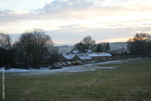 Dronfield, North East Derbyshire, England - December 3 2023: Snow dusting on stone barns at sunset in winter fields.