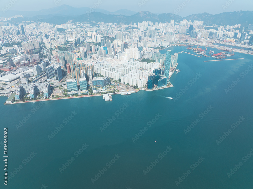 Fototapeta premium Aerial view of central Hong Kong, China. Expansive cityscape shows dense urban area meeting the sea. Buildings stretch towards distant mountains.