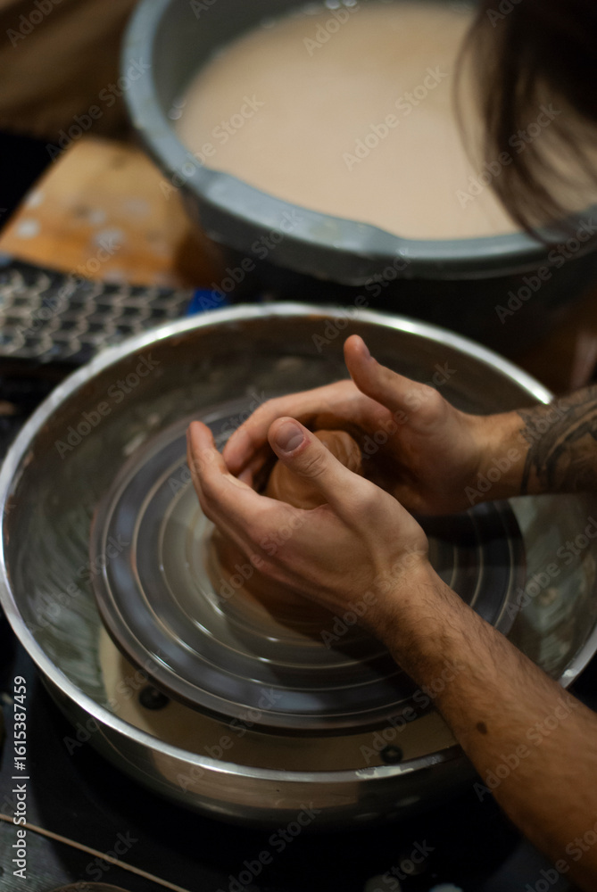 Fototapeta premium Hands shaping wet clay on a spinning pottery wheel 