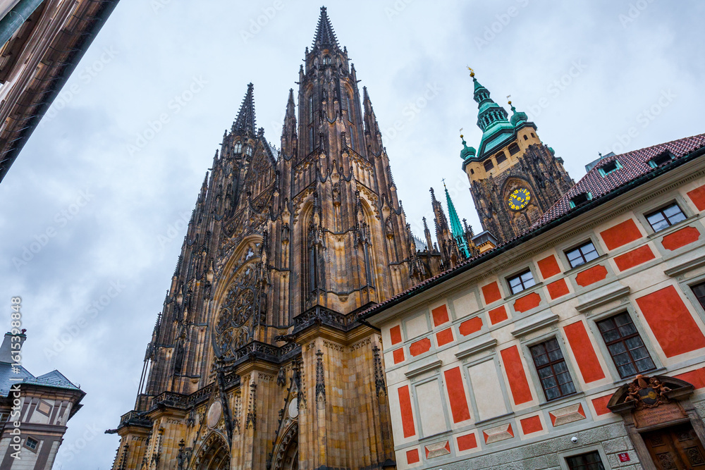 Fototapeta premium A wide view of St. Vitus Cathedral in Prague Castle, Prague, Czech Republic-Czechia, showcasing its monumental gothic architecture with intricate spires, arched windows and oxidized green copper roofs