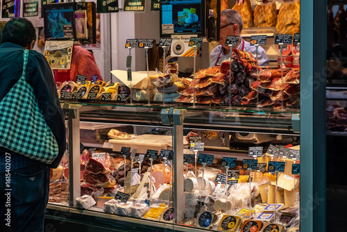 Canvastavla Meat and cheese delicatessen market stall displaying cured and smoked foods in a refrigerated cabinet for purchase