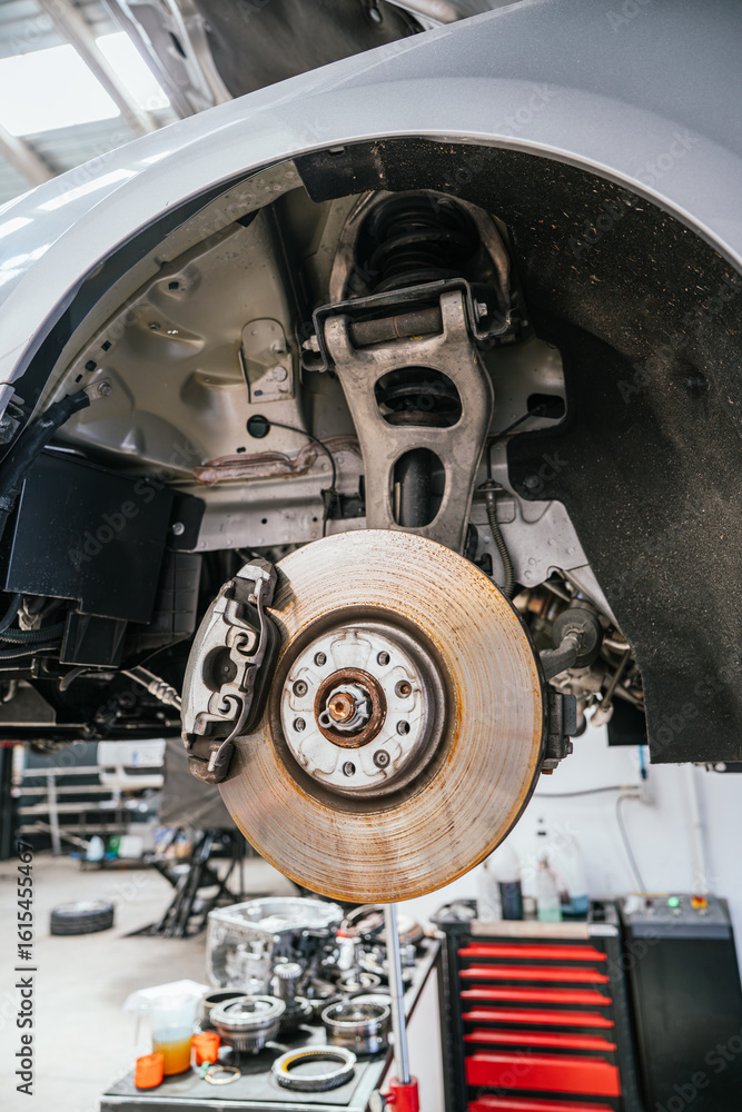 Exposed brake and suspension system on car undergoing repair Exposed brake and suspension system on car undergoing repair